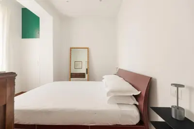 a bedroom with a bed with white sheets and a mirror at Vatican Lovely 2BR Apartment with Terrace in Rome