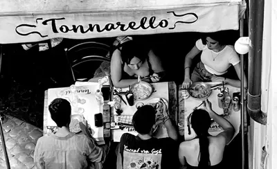 a group of people standing around a food stand at Anna’s home in Rome
