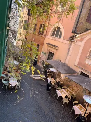 an outdoor cafe with tables and chairs and an umbrella at Anna’s home in Rome
