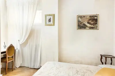 a bedroom with white walls and a bed and a window at Menotti elegant apartment in Rome