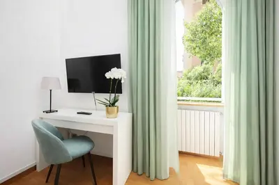 a desk with a television and a chair and a window at Luxury Apartment for 10 Central VATICANO S'Peter Basilica AirCond NETFLIX - SKY Wifi in Rome