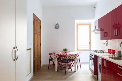a kitchen with red cabinets and a table with chairs at Flat Between The Vatican and Piazza del Popolo in Rome