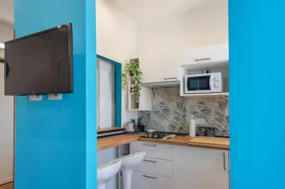 a kitchen with white cabinets and a tv on the wall at Casetta Tuscolana in Rome