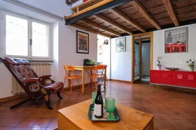 a living room with a table and a chair and a bottle of wine at Trastevere Characteristic Roman Home in Rome