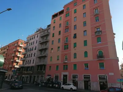 a tall pink building with cars parked in front of it at Etruria At San Giovanni by Halldis in Rome