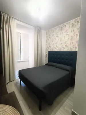 a bedroom with a bed with a blue headboard and a window at Nives House Roma in Rome