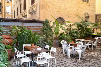 a patio with tables and white chairs and plants at Nives House Roma in Rome