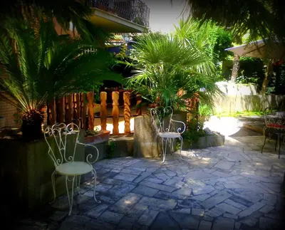 a patio with chairs and a fence with palm trees at Guest House Il Limone Nascosto in Rome
