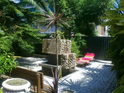 a garden with two chairs and a fountain with a palm tree at Guest House Il Limone Nascosto in Rome