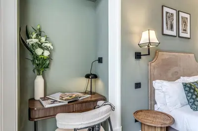 a bedroom with a table with a vase of flowers and a bed at Dimore Paganica in Rome