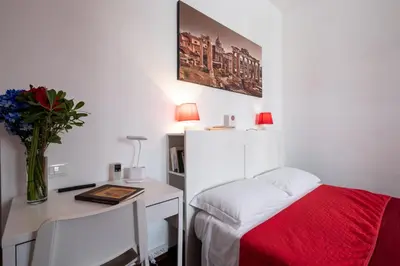 a bedroom with a desk and a bed with a red blanket at Take It Easy Roma Guest House in Rome