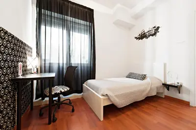a bedroom with a bed and a desk and a window at Take It Easy Roma Guest House in Rome