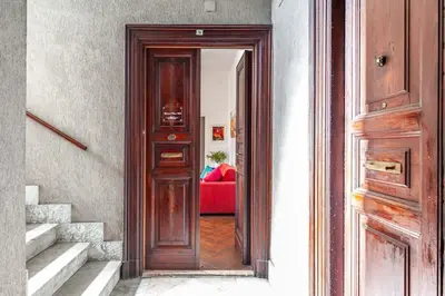a wooden door leading to a room with a red couch at Apartment Vatican Walls in Rome