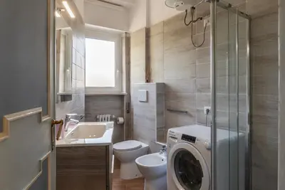 a bathroom with a toilet and a washing machine in it at GuestHost - 4 Winds Holiday Rental in Rome