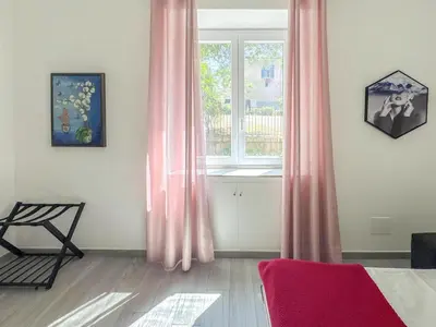 a room with a window with pink curtains and a chair at Appartamento per 4 persone a Garbatella - My Garba in Rome