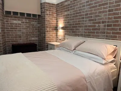 a bedroom with a white bed with a brick wall at Casina Dacia in Rome