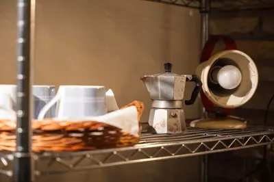 a shelf with a coffee maker and a plate of food at TWO-ROOM Apt. under the Aqueduct's ARCH in Pigneto in Rome