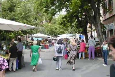 a group of people walking down a sidewalk at an outdoor market at TWO-ROOM Apt. under the Aqueduct's ARCH in Pigneto in Rome