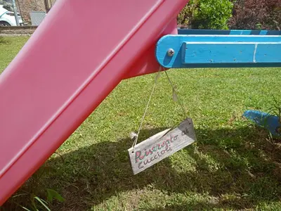 a sign hanging from a slide in a playground at TWO-ROOM Apt. under the Aqueduct's ARCH in Pigneto in Rome