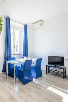 a dining room with blue chairs and a table and a tv at Maison Blu - in Trastevere in Rome
