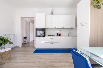 a kitchen with white cabinets and a blue rug at Maison Blu - in Trastevere in Rome
