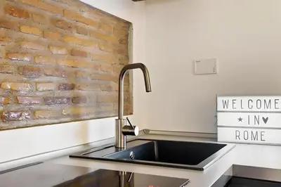 a kitchen with a sink and a brick wall at HostMe Piazza Navona Apartament in Rome