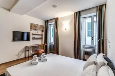 a bedroom with a bed and a desk and a tv at Domus Mondrian Luxury House in Rome