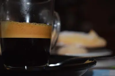 a glass of coffee on a table with a plate of food at Boezio43B&B in Rome