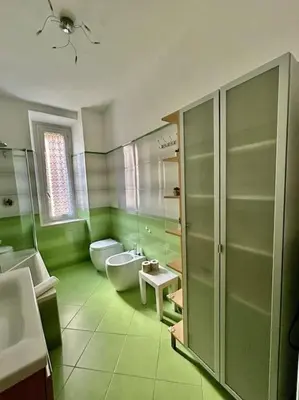 a green bathroom with a toilet and a tub and a sink at Angel House - balcony and view in Rome