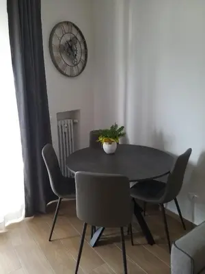 a dining room table with chairs and a clock on the wall at Casa di Alice in Rome