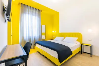 a bedroom with a bed and a table and a yellow wall at Luciano San Giovanni Guest House in Rome
