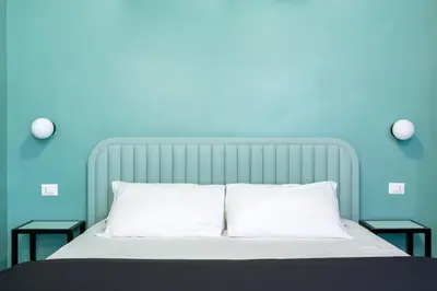 a bed with a blue wall and two night stands next to it at Luciano San Giovanni Guest House in Rome