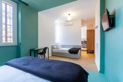 a bedroom with a bed and a couch and a television at Luciano San Giovanni Guest House in Rome