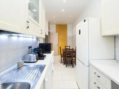a kitchen with white cabinets and a sink and a table at {Colosseum 10 minutes} Netflix & Free Wi-Fi in Rome