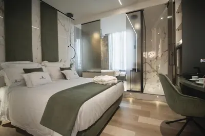 a bedroom with a large white bed and a desk at Tritone Luxury Suites Fontana di Trevi in Rome