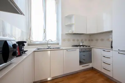 a white kitchen with white cabinets and a sink at Lucrezio Caro Luxury Apartment in Rome