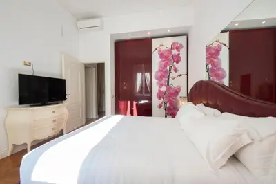 a bedroom with a large white bed and a television at Lucrezio Caro Luxury Apartment in Rome