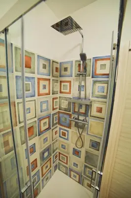 a shower stall with a wall of framed pictures at P88 guesthouse in Rome