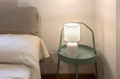 a green table with a lamp on it next to a bed at Eri's Apartment in Rome