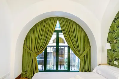 a bedroom with a large window with green curtains at Lion Aparts Rome in Rome