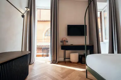 a bedroom with a bed and a desk with a television at The Flow - Via Del Corso in Rome