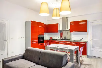 a kitchen with red cabinets and a table and a couch at Lion Aparts Rome - Vatican City in Rome