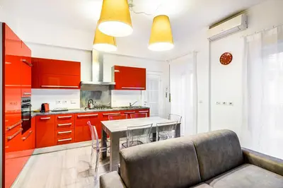 a kitchen with red cabinets and a table with a couch at Lion Aparts Rome - Vatican City in Rome