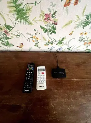 two remote controls sitting on top of a wooden table at 129 Gallery’s Studio @ Vatican in Rome