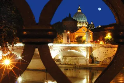 a view of a building and a bridge at night at Liberty Rome Suites - Liberty Collection in Rome