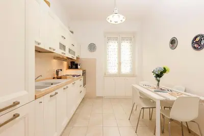 a kitchen with white cabinets and a table and chairs at Delizioso apartment Porta Metronia Roma in Rome