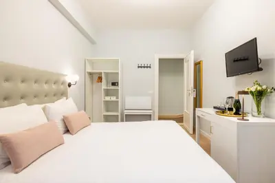 a white bedroom with a white bed and a television at Domus Bella Roma in Rome