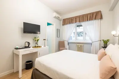 a bedroom with a bed and a desk and a window at Domus Bella Roma in Rome