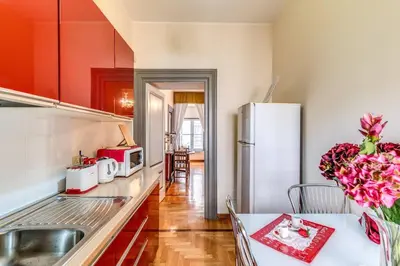 a kitchen with red cabinets and a white refrigerator at XX SETT: Flat by Barberini Trevi Fountain in Rome