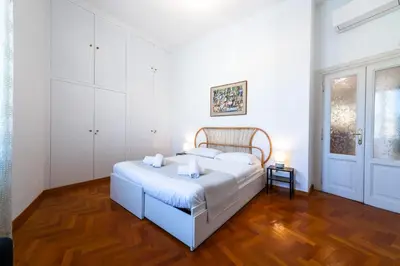 a white bedroom with a bed and a wooden floor at Casa Emme in Rome